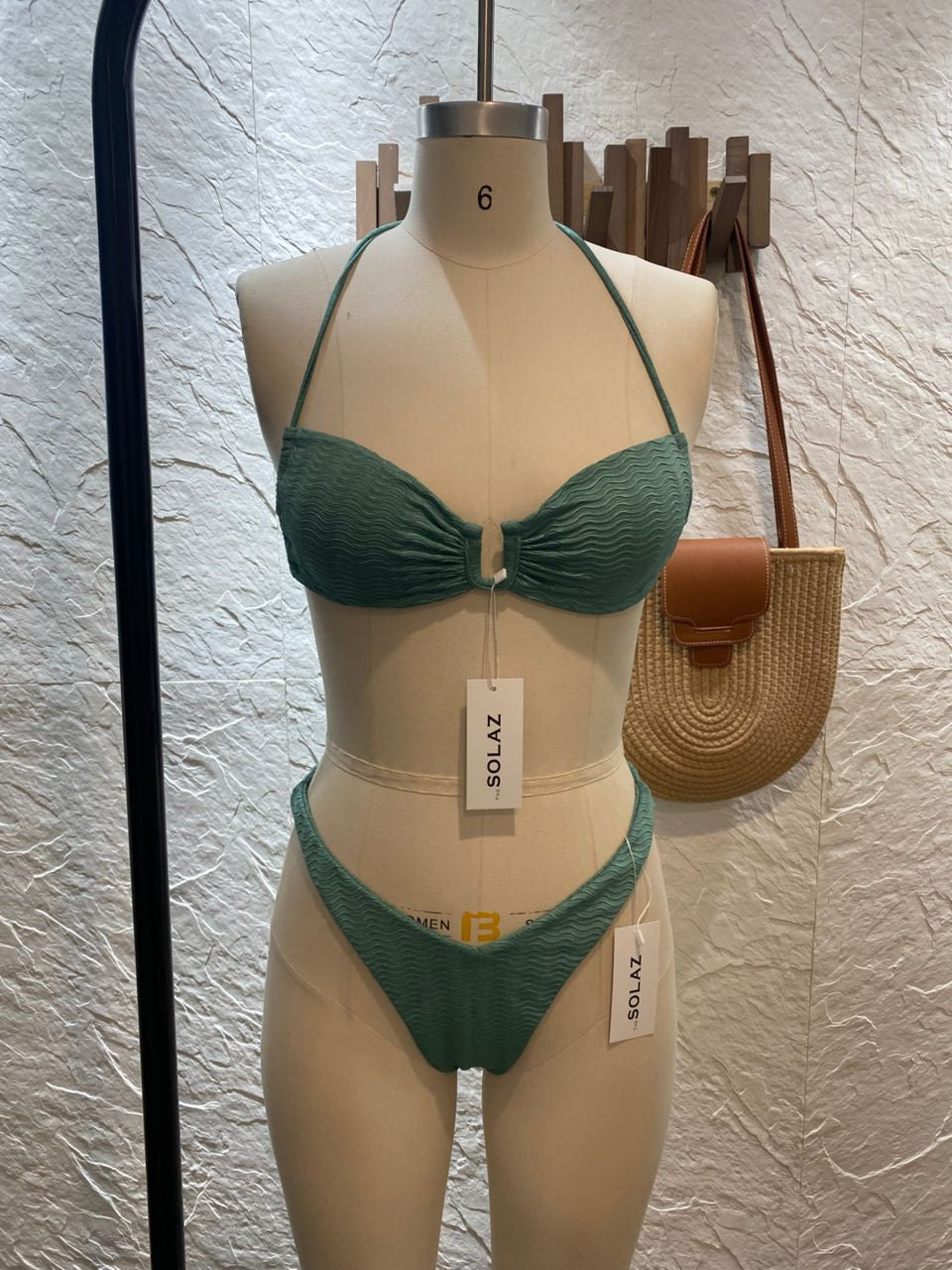 This image features a model showcasing the Calla Bikini Teal TOP, part of a stylish beachwear set. The bikini top is designed as a bandeau style with a distinct tea/greenl color.